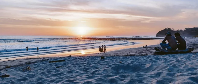 Sunset at the beach in Nosara — surfers and beach walkers at the waterline