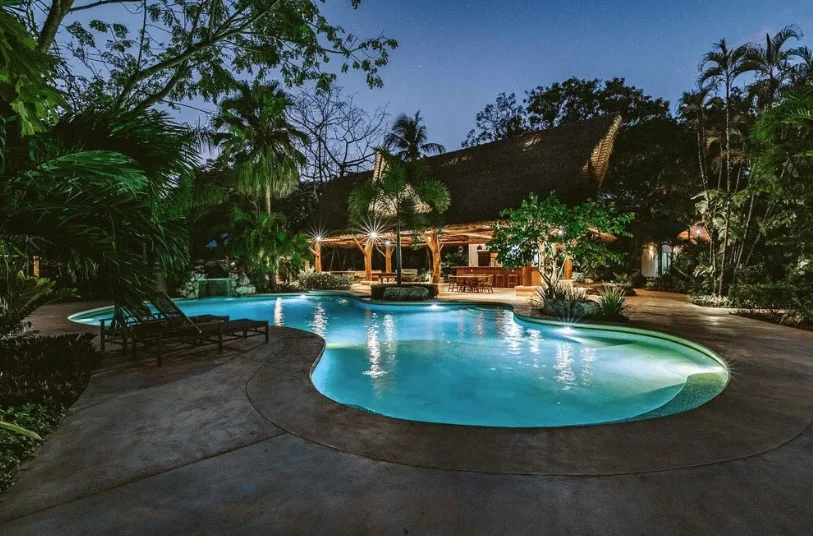 The pool at dusk, lit up in front of the open-air rancho